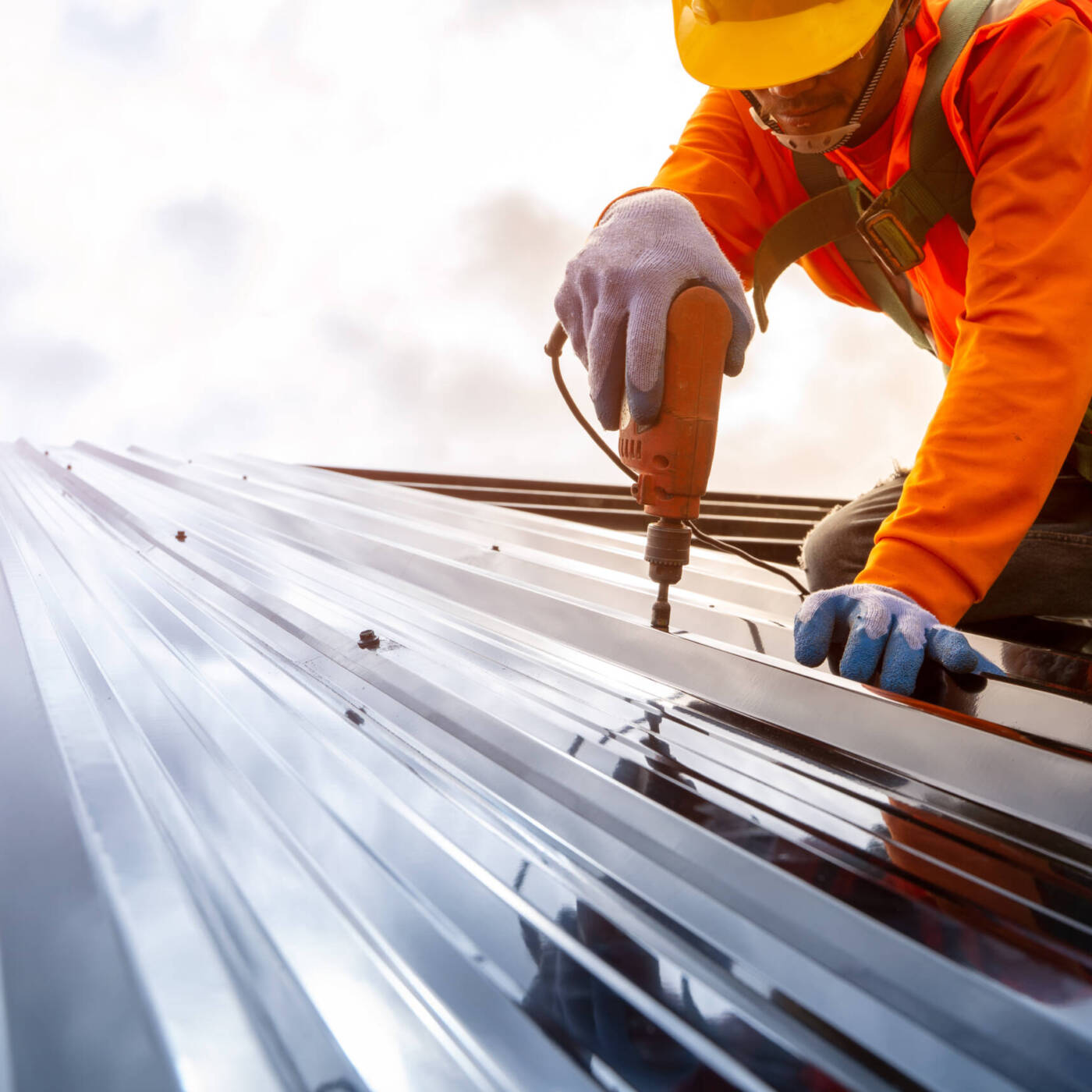 Construction worker using drill on metal roof panels